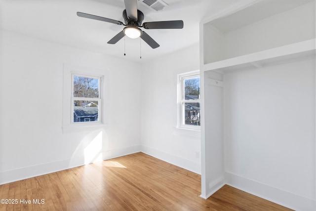 empty room with baseboards, wood finished floors, visible vents, and a healthy amount of sunlight