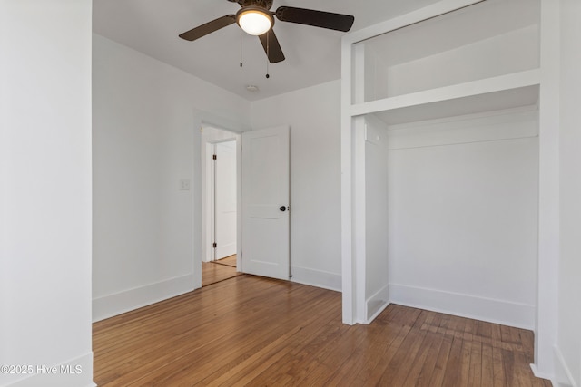 unfurnished bedroom featuring a closet, wood finished floors, a ceiling fan, and baseboards