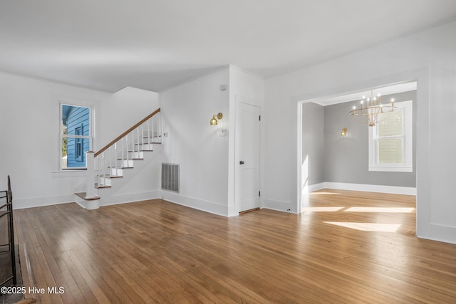 unfurnished living room featuring stairway, visible vents, light wood finished floors, and a wealth of natural light