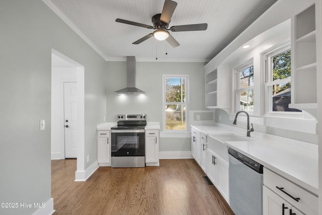 kitchen featuring appliances with stainless steel finishes, light countertops, wall chimney range hood, open shelves, and a sink