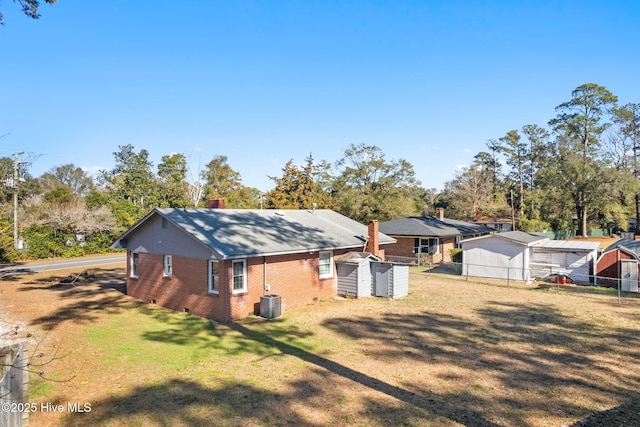 rear view of house featuring central AC, a shed, and a lawn