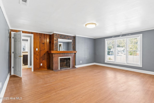 unfurnished living room featuring crown molding, a fireplace, and light wood-type flooring