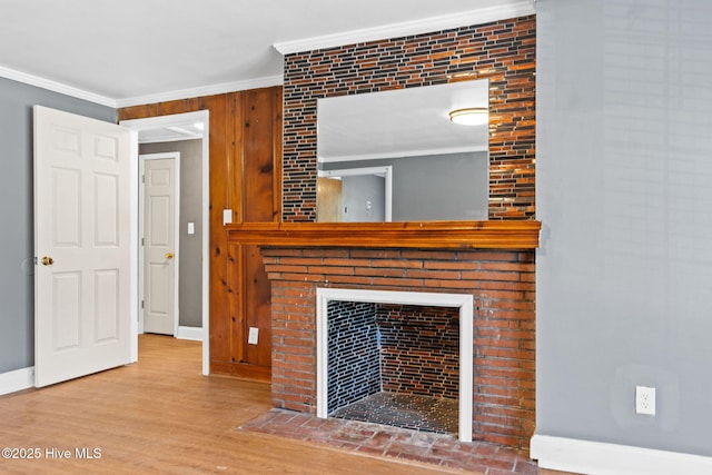 unfurnished living room featuring hardwood / wood-style flooring, ornamental molding, and a brick fireplace