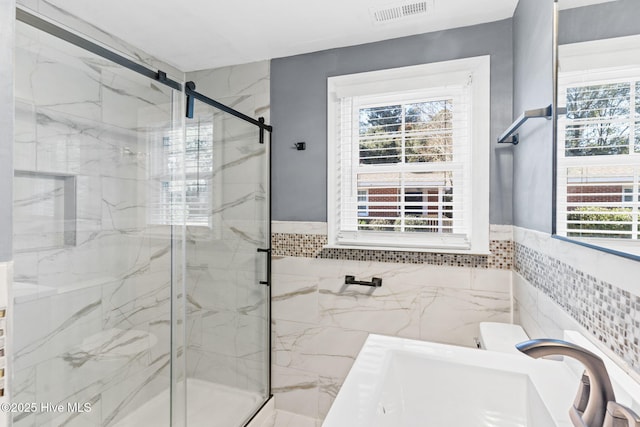 bathroom with vanity, toilet, a shower with door, and tile walls