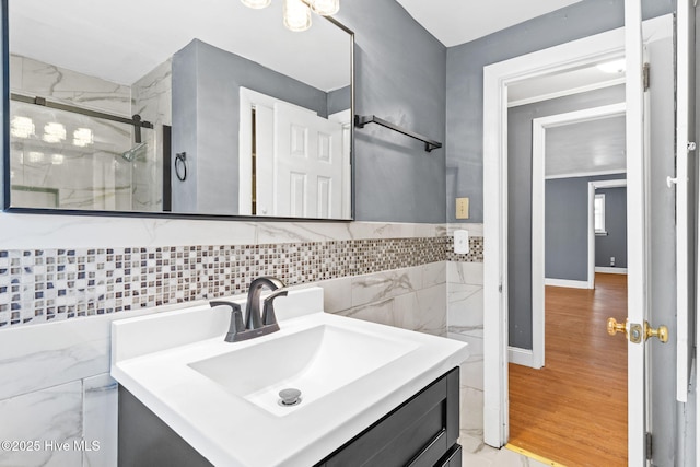 bathroom with a shower with door, vanity, wood-type flooring, and tile walls