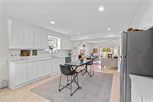 kitchen with light hardwood / wood-style flooring, sink, stainless steel appliances, and white cabinetry