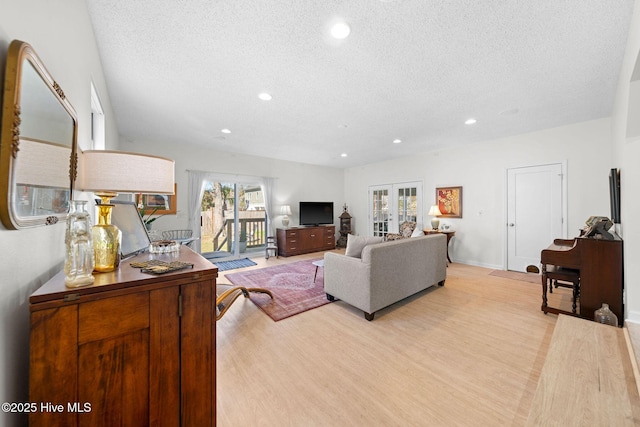 living room featuring a textured ceiling, french doors, and light hardwood / wood-style floors