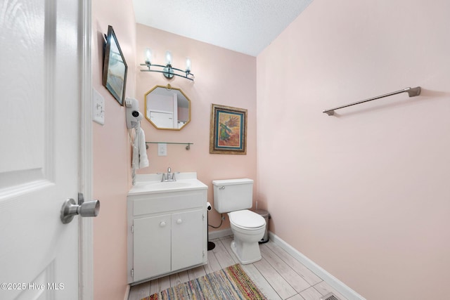 bathroom featuring a textured ceiling, vanity, and toilet