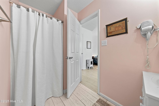 bathroom featuring vanity, wood-type flooring, and a textured ceiling