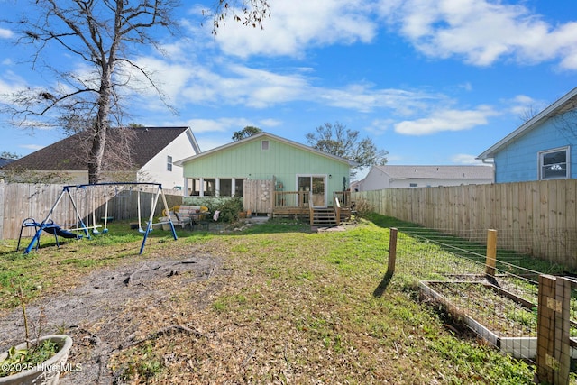 rear view of house with a playground, a lawn, and a wooden deck