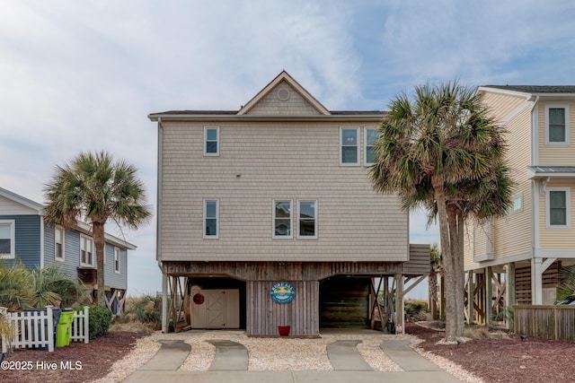 view of front facade featuring a garage, a carport, driveway, and fence