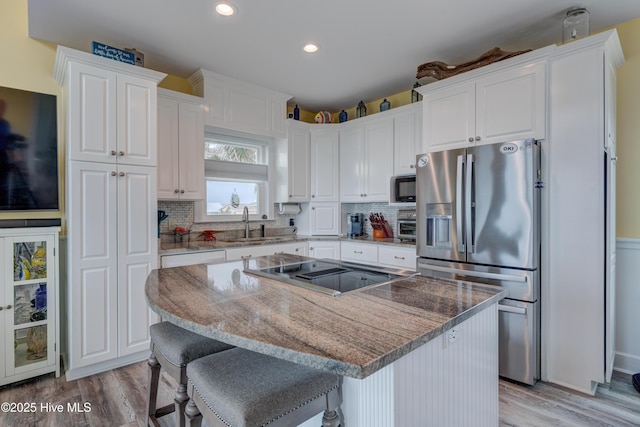 2017 W Beach Dr, Oak Island, NC 28465 - kitchen featuring stainless steel fridge with ice dispenser, built in microwave, white cabinets, light wood-type flooring, and recessed lighting