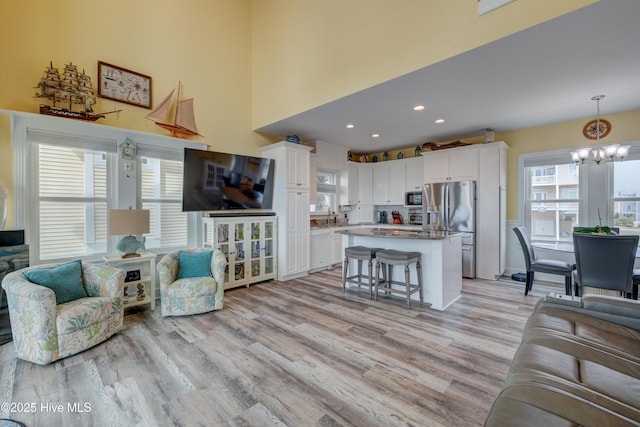 2017 W Beach Dr, Oak Island, NC 28465 - living room featuring light wood-style floors, plenty of natural light, a chandelier, a high ceiling, and recessed lighting