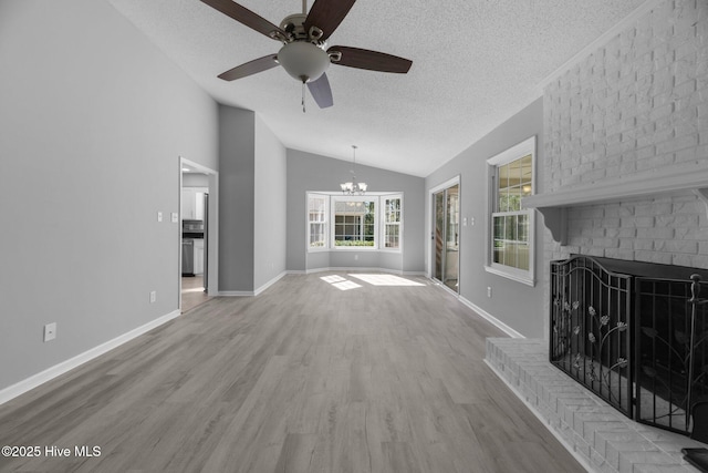 unfurnished living room featuring a textured ceiling, a fireplace, baseboards, vaulted ceiling, and light wood-style floors