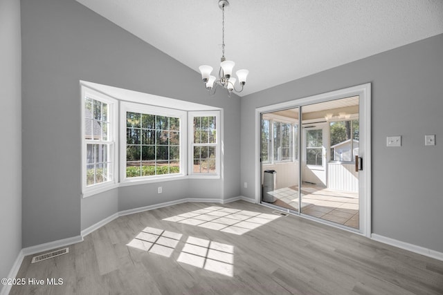 unfurnished dining area with light wood-type flooring, a wealth of natural light, visible vents, and lofted ceiling