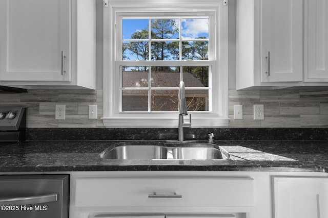 kitchen with tasteful backsplash, dark stone counters, dishwasher, white cabinetry, and a sink