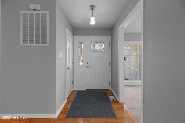 entryway with light wood-style flooring, visible vents, and baseboards