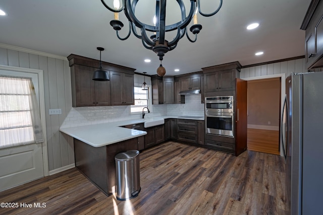 kitchen with sink, a breakfast bar area, decorative light fixtures, kitchen peninsula, and stainless steel appliances