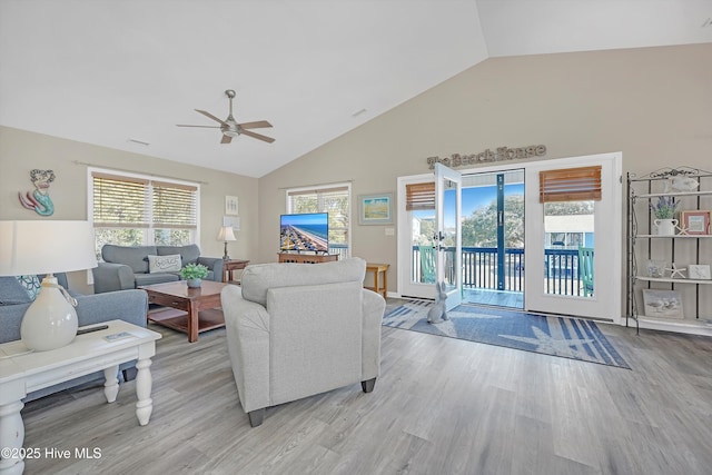 living room featuring light wood-style floors, visible vents, high vaulted ceiling, and a ceiling fan