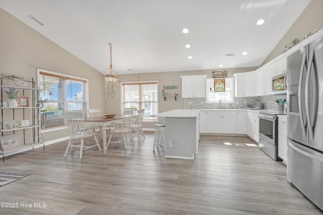 kitchen featuring stainless steel appliances, lofted ceiling, light countertops, visible vents, and white cabinets