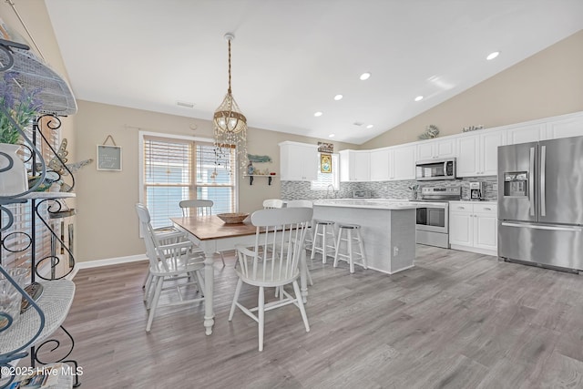 dining room featuring a healthy amount of sunlight, light wood finished floors, and an inviting chandelier