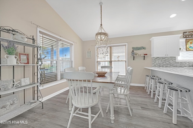 dining area featuring a wealth of natural light, vaulted ceiling, baseboards, and wood finished floors