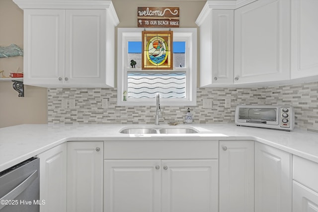 kitchen with tasteful backsplash, a sink, and white cabinets