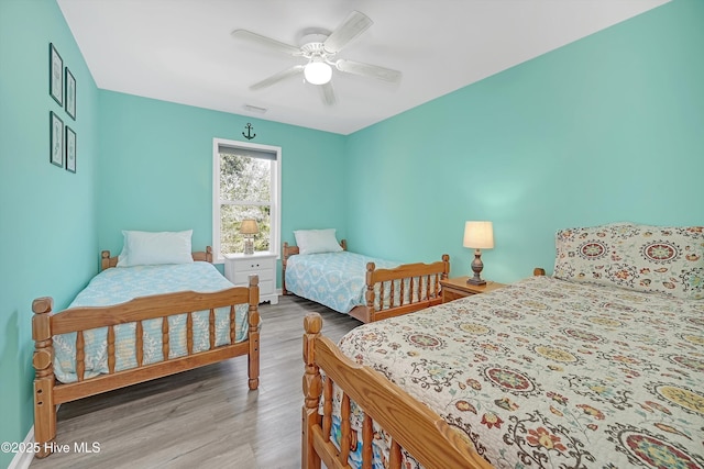 bedroom with ceiling fan, wood finished floors, and visible vents