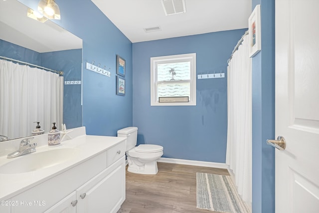 bathroom featuring toilet, wood finished floors, visible vents, and baseboards