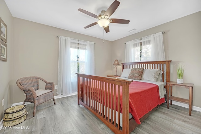 bedroom with light wood-type flooring, visible vents, ceiling fan, and baseboards