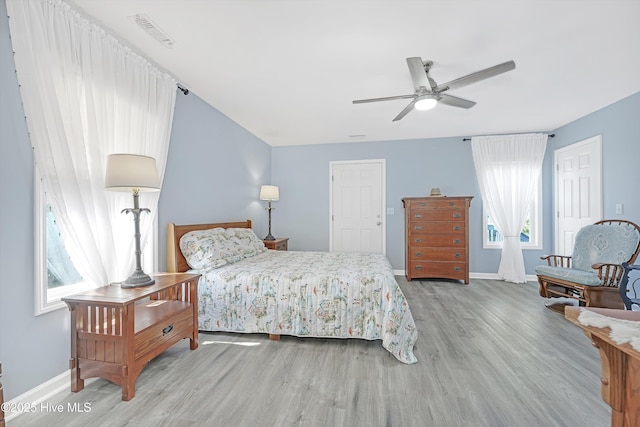 bedroom featuring a ceiling fan, visible vents, baseboards, and wood finished floors