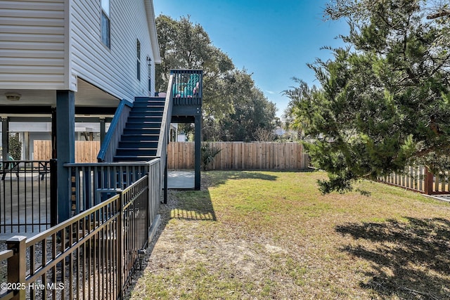 view of yard featuring a fenced backyard, a wooden deck, and stairs