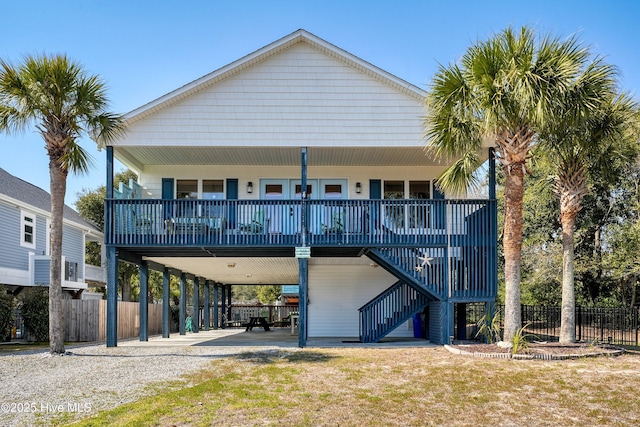 rear view of property with a porch, stairway, fence, a carport, and driveway