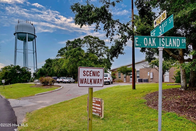 community / neighborhood sign with uncovered parking and a yard