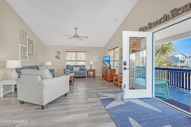 living room featuring lofted ceiling, light wood finished floors, a ceiling fan, and baseboards