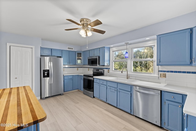 kitchen with sink, backsplash, blue cabinets, ceiling fan, and stainless steel appliances