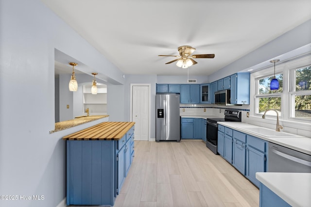 kitchen with sink, blue cabinetry, stainless steel appliances, and decorative light fixtures