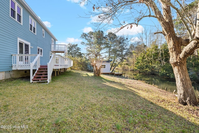 view of yard featuring a deck with water view and an outdoor structure