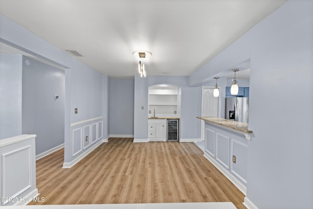 unfurnished living room with light hardwood / wood-style flooring, indoor wet bar, and wine cooler