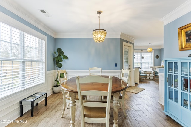 dining space featuring light wood-type flooring, a chandelier, and crown molding