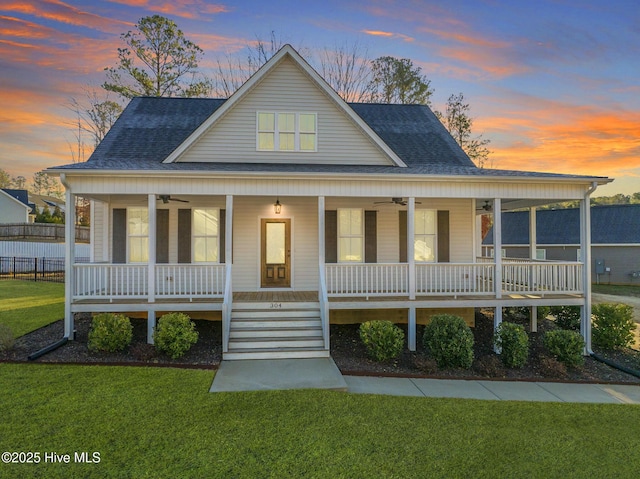 farmhouse featuring a ceiling fan, a lawn, covered porch, and a shingled roof