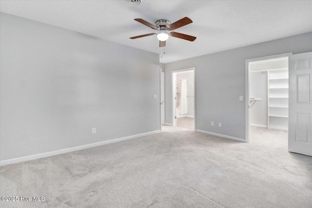 unfurnished bedroom featuring connected bathroom, a textured ceiling, a spacious closet, light colored carpet, and a closet