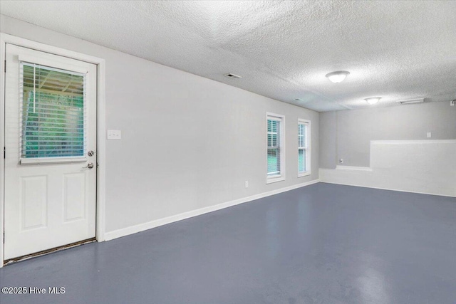 unfurnished room with concrete flooring and a textured ceiling