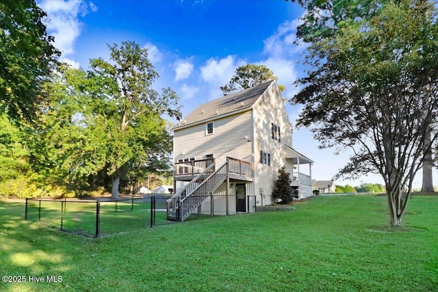 rear view of house with a wooden deck and a lawn