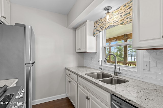 kitchen with a sink, appliances with stainless steel finishes, white cabinetry, tasteful backsplash, and light stone countertops