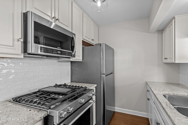 kitchen with light stone countertops, white cabinetry, baseboards, and stainless steel appliances