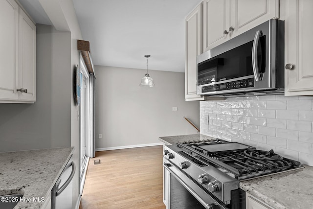 kitchen featuring decorative backsplash, light wood-style flooring, light stone countertops, appliances with stainless steel finishes, and white cabinets