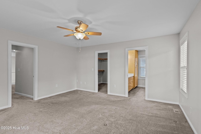 unfurnished bedroom featuring light colored carpet, a spacious closet, visible vents, baseboards, and a closet