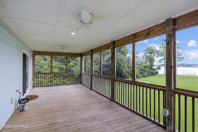 unfurnished sunroom featuring a ceiling fan and a water view