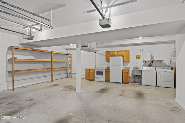 garage featuring freestanding refrigerator, washing machine and clothes dryer, a sink, and a garage door opener